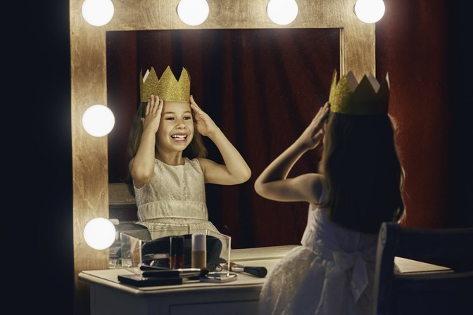 jeune fille avec une couronne sur la tête se regarde dans un miroir