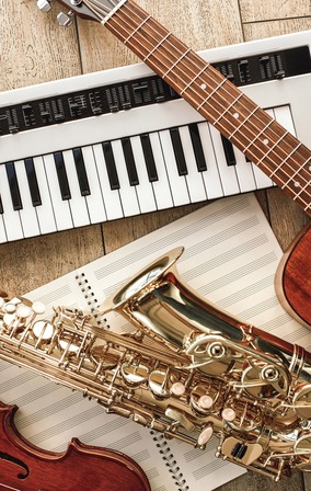 clavier piano saxophone sur un cahier guitare électrique posés sur une table