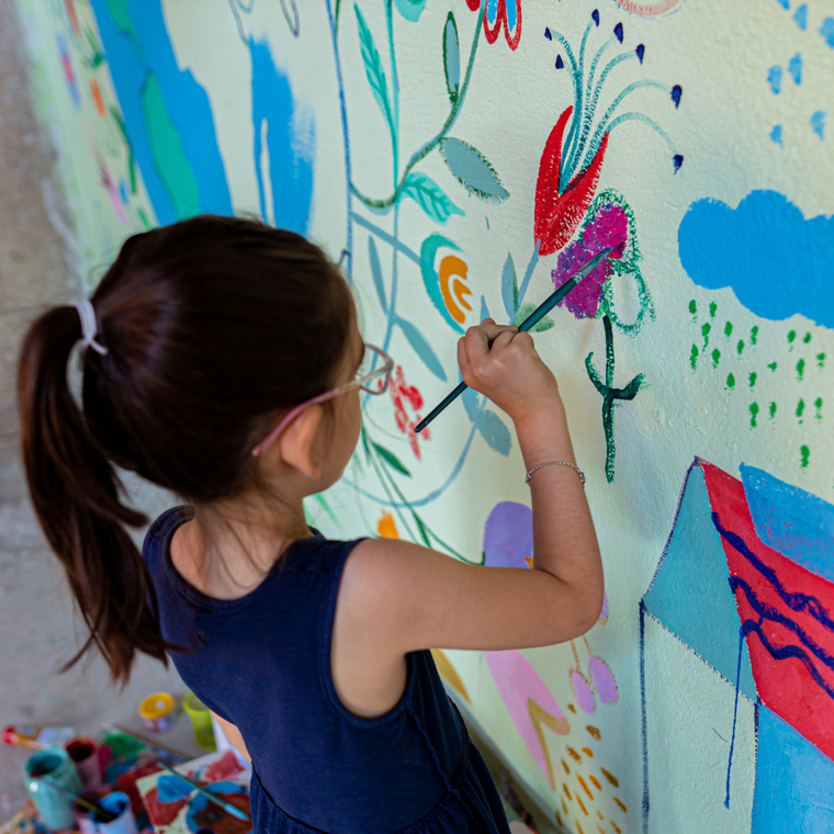 enfant peint une fleur sur un mur