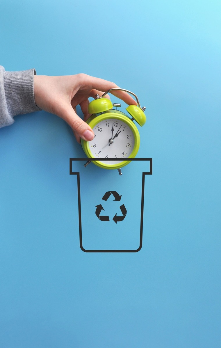 une main dépose une horloge dans une poubelle "recyclée"