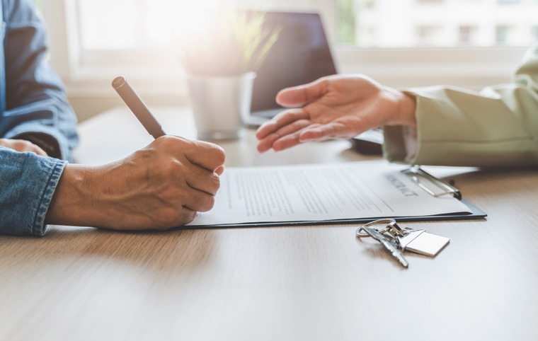 2 personnes lors d'une signature d'un document clé en avant plan