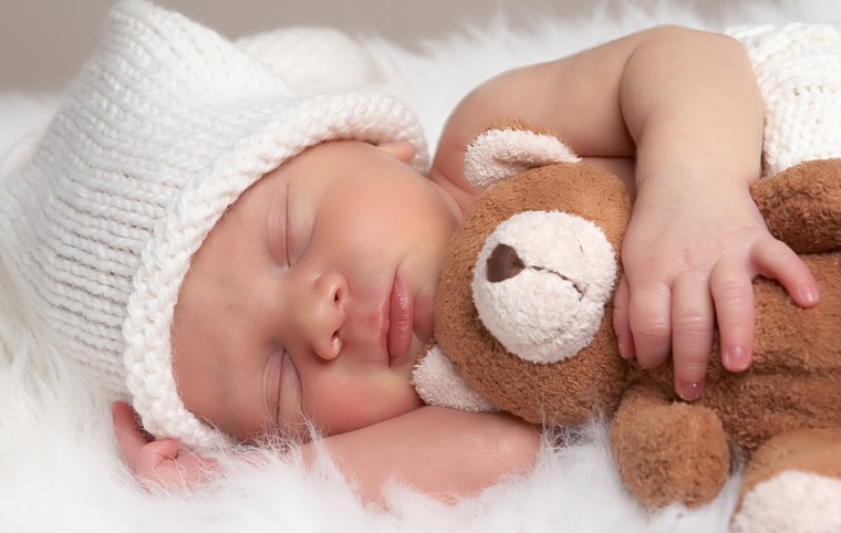 un nouveau-né dort et tient un doudou