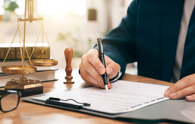 une personne signe un document balance de la justice en arrière-plan