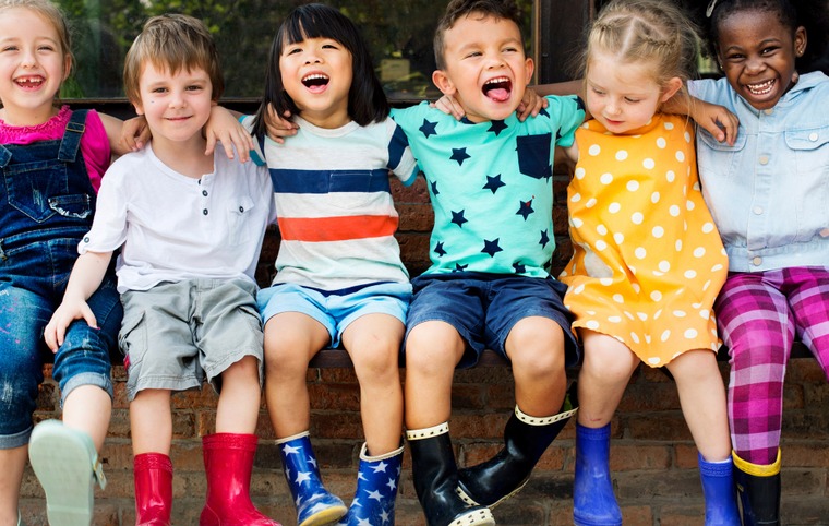 6 enfants assis l'un à côté de l'autre sourient